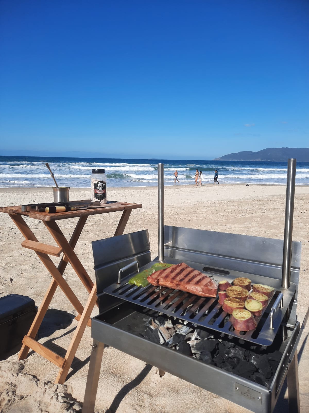 Churrasqueira portátil Ecker Spirit cravada na areia da praia ao pôr do sol